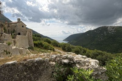 Scenic view of mountains and buildings against cloudy sky