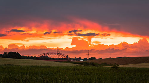 Scenic view of dramatic sky over land during sunset