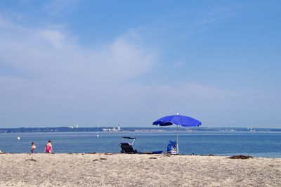 Parasol and chair at beach against sky