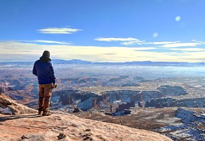 Rear view of man standing on mountain against sky