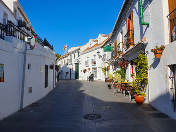 Street amidst buildings in city against clear blue sky