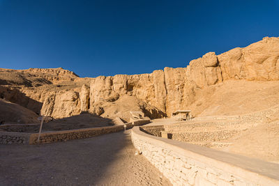 Road amidst rocks against clear blue sky