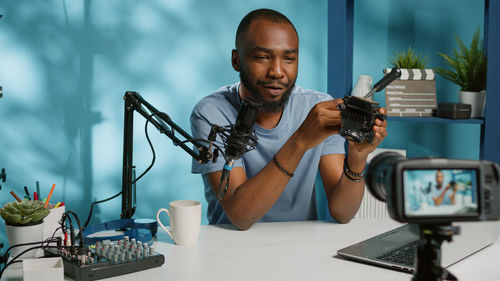 Young man vlogging on camera at desk