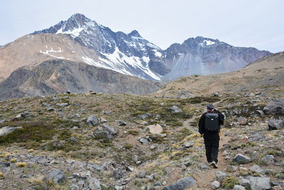 Rear view of man walking on mountain against sky