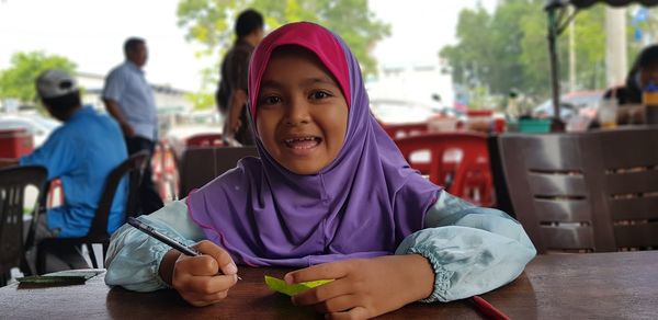 Portrait of smiling girl sitting on table