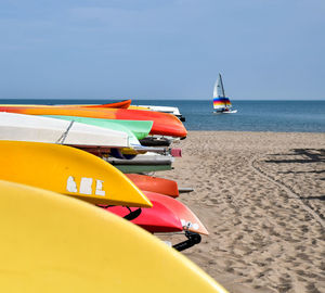 Deck chairs on beach against sky