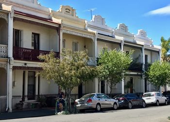 Cars on road by buildings against sky in city