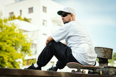 Young man wearing sunglasses standing against built structure