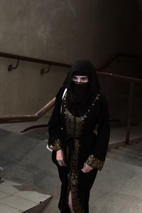 A muslim woman rises from a dark passage stairs trembling with fear.