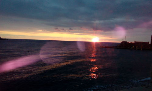 Scenic view of sea against dramatic sky during sunset