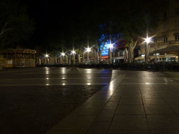 Illuminated street amidst buildings in city at night