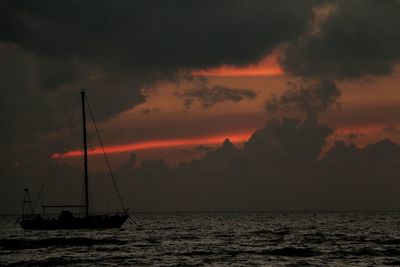 Silhouette sailboat sailing on sea against sky during sunset