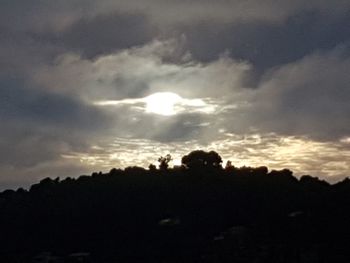 Silhouette of trees against cloudy sky