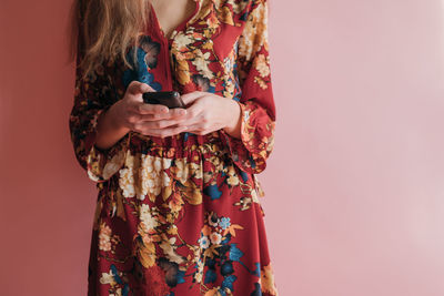 Midsection of woman holding smart phone against gray background