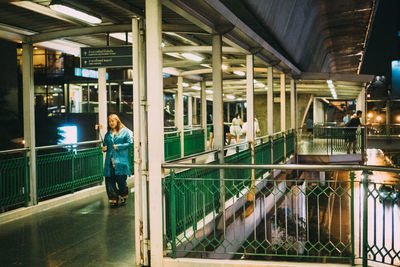 Reflection of woman standing on illuminated bridge in building