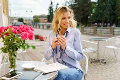 Young woman holding flower bouquet on table