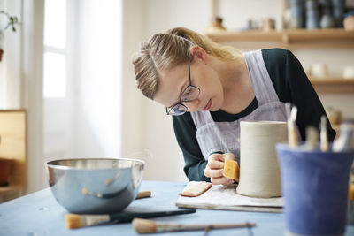 Young woman molding pot in pottery class