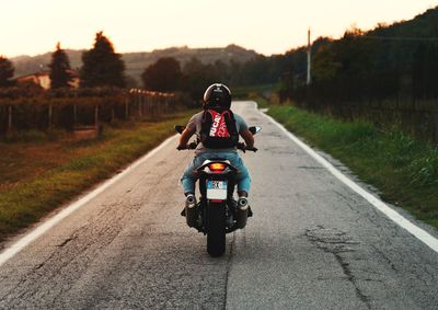 Rear view of man riding motorcycle on road