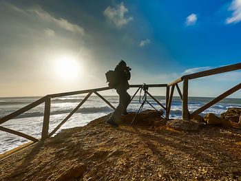 Man standing on railing against sea