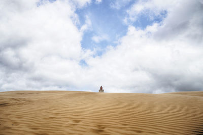 Scenic view of desert against cloudy sky