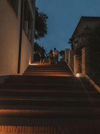 Low angle view of steps amidst buildings against sky at night