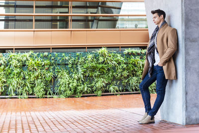 Full length of young man standing against building