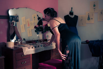 Side view of woman wearing dress looking into mirror at studio