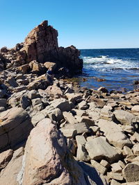 Rock formation on beach against clear blue sky