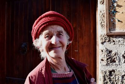 Portrait of smiling senior woman against door