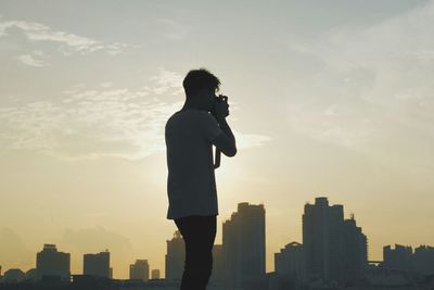 Silhouette of woman in city at sunset