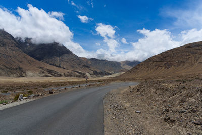 Road by mountains against sky