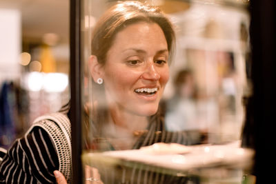 Smiling woman looking at earrings in fashion store