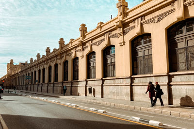 People walking on road by buildings in city