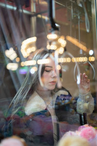 Woman looking at illuminated glass window