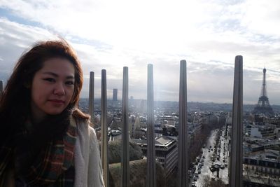 Portrait of beautiful woman standing by cityscape against sky