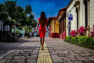 Rear view of woman walking on footpath in city