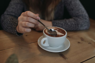 Midsection of woman having coffee at table