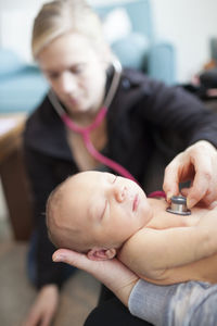 Doctor examining newborn baby boy held by mother