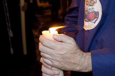 Close-up of man holding burning candle