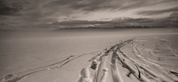 Panoramic view of tire tracks on snow covered landscape