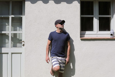 Portrait of young man standing against wall