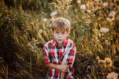 High angle portrait of boy sitting on field amidst plants