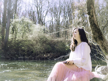 Side view of young woman standing against waterfall