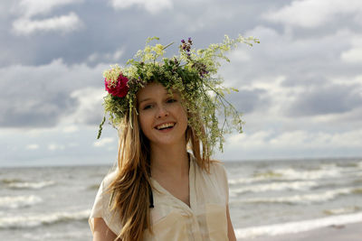 Portrait of smiling young woman by sea against sky