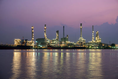 Illuminated factory against sky at night