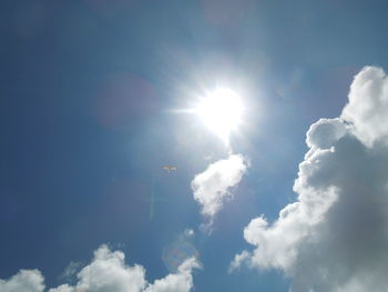 Low angle view of sun shining through clouds