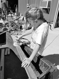 High angle view of girl sanding wood using sander in back yard