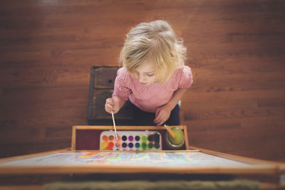 High angle view of girl painting on canvas at home