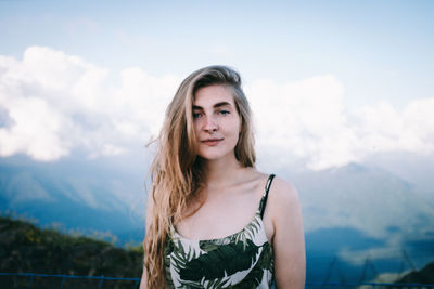Portrait of smiling woman standing against mountains