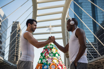 Side view of males holding hands standing against building